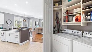 Una cocina moderna con una isla central, electrodomésticos integrados y un área de lavandería con lavadora y secadora.