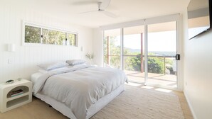 A bedroom with a bed, a nightstand, a window, and a sliding glass door leading to a balcony. - Shelby Shores (whole house) (Crescent Head)