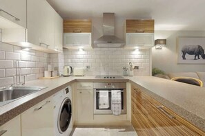 A modern kitchen with a built-in washing machine, a stove, and a microwave.