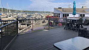 A deck with a table and chairs, overlooking a marina with boats.