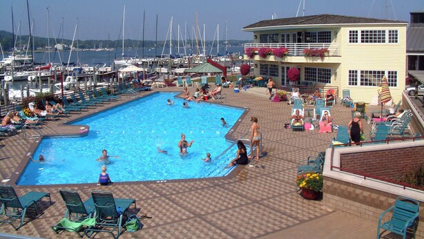 A swimming pool area with lounge chairs and a building with a balcony overlooking the water.