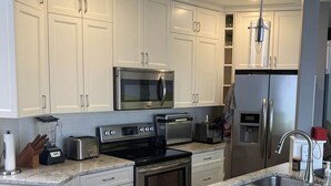A modern kitchen with white cabinetry, stainless steel appliances, and a granite countertop.