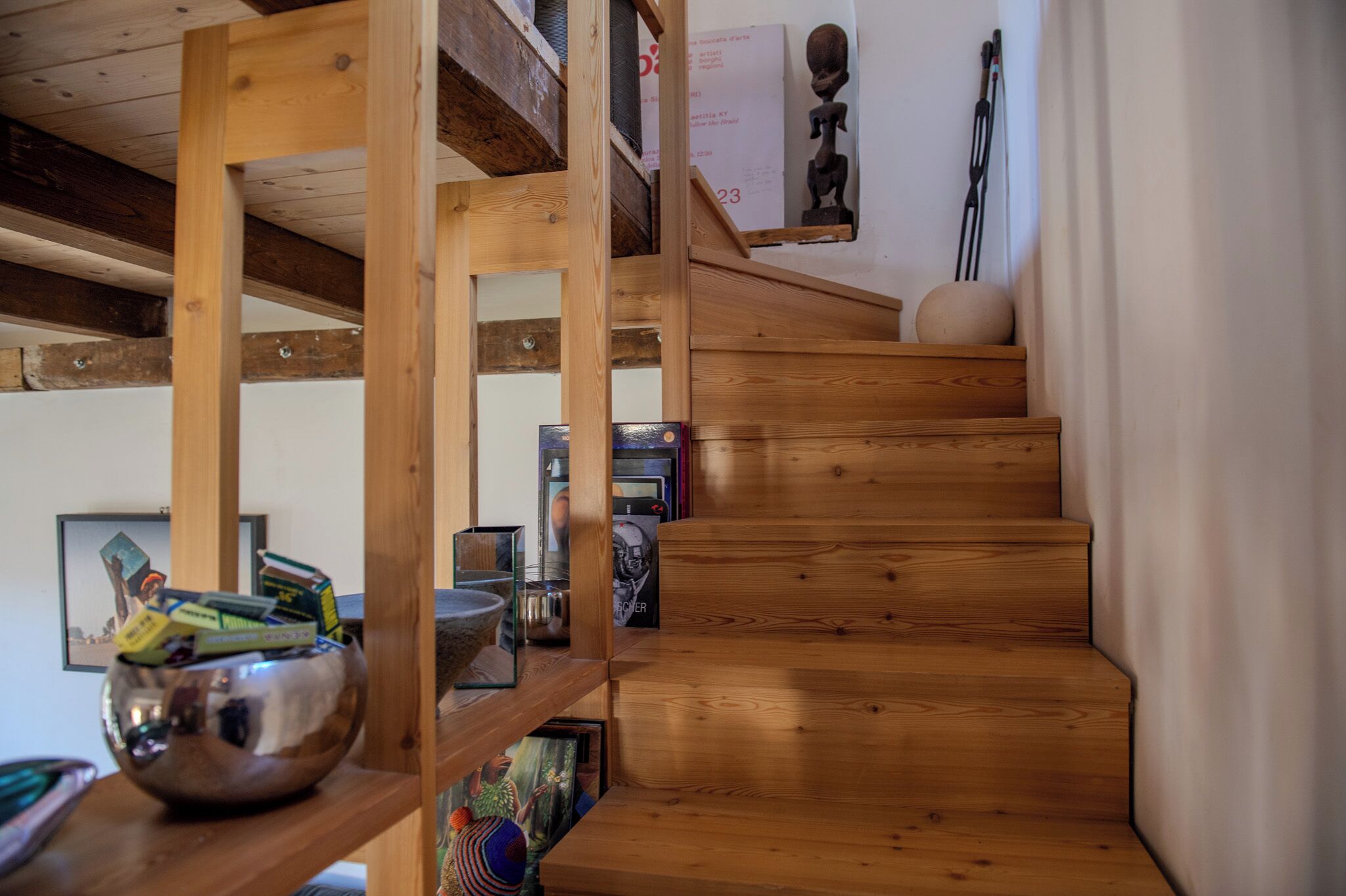 A wooden staircase with a metal bowl on the left and a framed picture below.