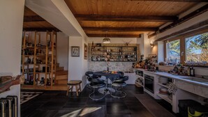 Eine moderne Küche mit einer zentralen Kochinsel, einer Bar und einer Holztreppe, die zu einem erhöhten Bereich führt.