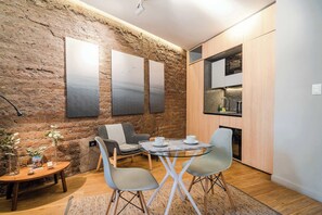 Eine moderne Küche mit einer Steinwand, einem Essbereich mit einem Glastisch und einer Couch.