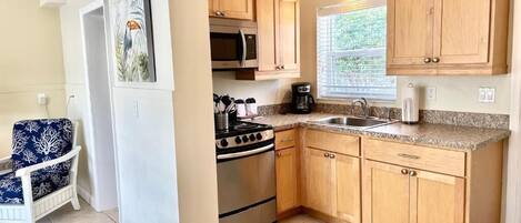 A kitchen with wooden cabinets, a stainless steel stove, a microwave, and a coffee maker.
