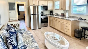 A compact kitchen with modern appliances, a dining area with a sofa, and a large window providing natural light. - Matecumbe Resort (Islamorada)