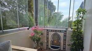 Une véranda dotée d’un sol carrelé, d’un banc, de plantes en pot et d’un mur décoratif.