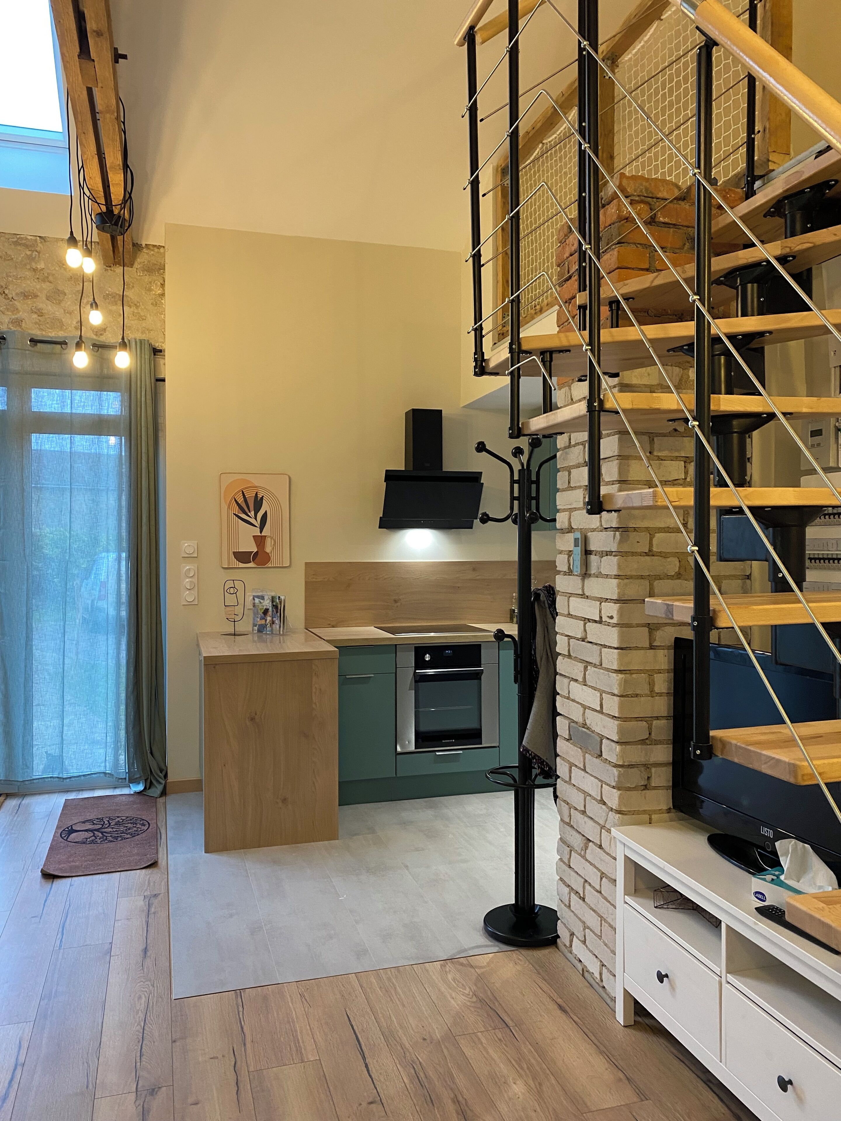 A modern kitchen with a built-in oven, a wooden counter, and a staircase with a metal railing.