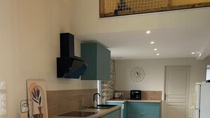 Une cuisine moderne avec des meubles de couleur turquoise, un plan de travail en bois et un four encastré.