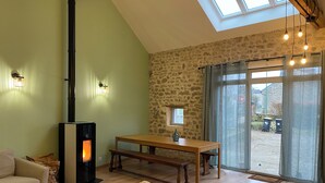 Un salon chaleureux avec un mur en pierre, un banc en bois, un canapé et une cheminée.
