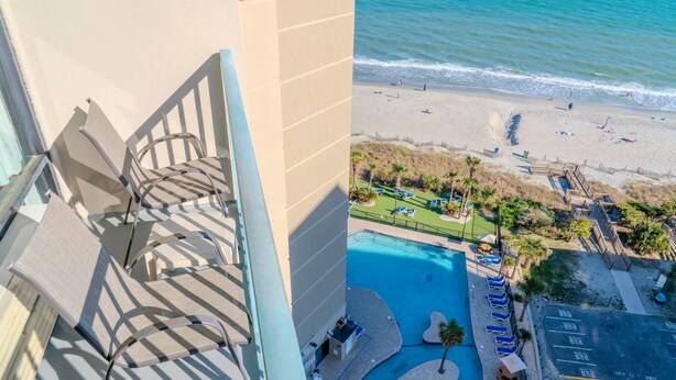 Una piscina con lettini, una spiaggia e un edificio con un balcone.