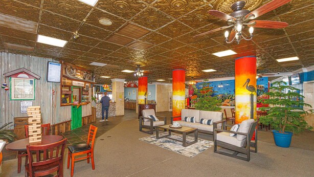 A lobby with a high ceiling, wooden chairs, a coffee table, and a bar area.