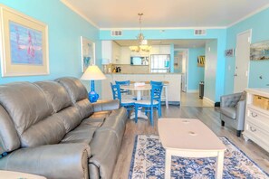 A living room with a sofa, a coffee table, and a dining area with chairs.