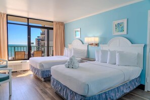 Habitación de hotel con dos camas, vista al océano, balcón y una silla.