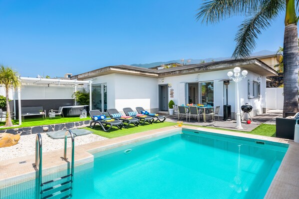 Ein Swimmingpool mit Liegestühlen, ein Grillplatz und eine Terrasse mit Gartenmöbeln.