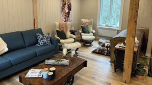 Ein Wohnzimmer mit einer Couch, zwei Sesseln, einem Couchtisch und einem Fenster mit Blick.