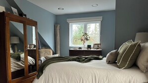 Ein Schlafzimmer mit einem großen Bett, einem Holzschrank, einem Fenster mit Blick und einem Nachttisch mit Lampe.