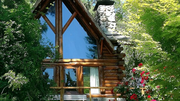 A log cabin with a stone chimney, wooden windows, and a stone fireplace. - Willow log cabin (Mar de las Pampas)