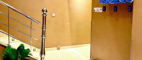 Een hotel lobby met een marmeren trap, een plant en een muurbevestigde zeepdispenser.