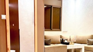 A modern living room with a sofa, a coffee table, and a small round table with a stool. - Residence America (Dakhla)