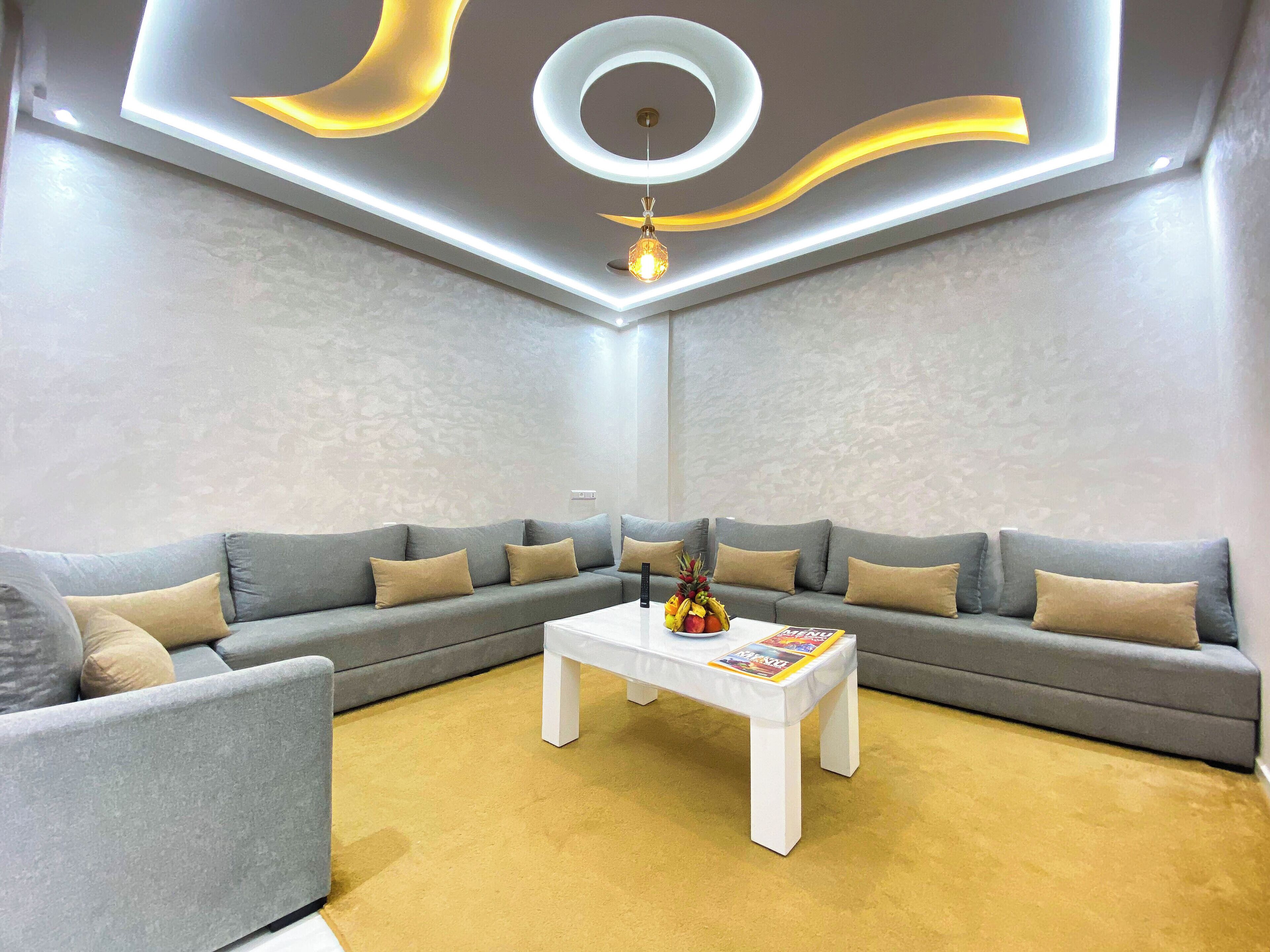 A modern living room with a sectional sofa, a coffee table, and a decorative light fixture.
