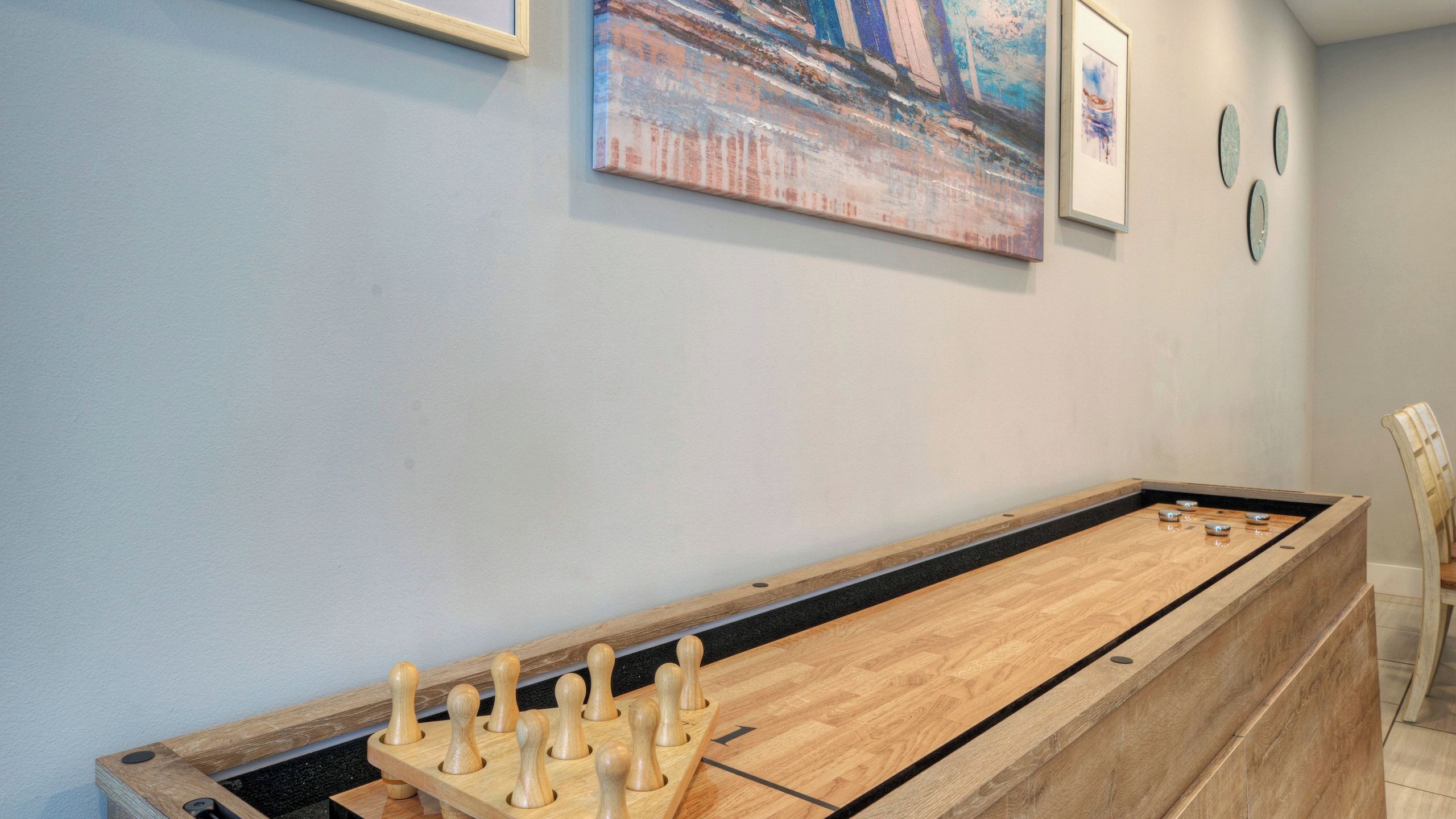 Una mesa de fútbolín en una habitación con pared azul claro, un cuadro y una silla.
