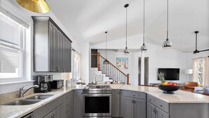 A modern kitchen with grey cabinets, stainless steel appliances, and a large island. - 7bdr w/ Private Pool, Hot Tub, Fire Pit, Walk to Beach Tidal Wave by Avantstay (Destin)