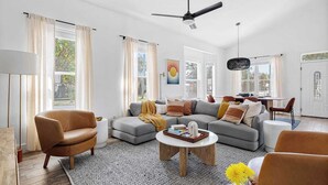 A spacious living room with a modern sofa set, a coffee table, and a ceiling fan. - 7bdr w/ Private Pool, Hot Tub, Fire Pit, Walk to Beach Tidal Wave by Avantstay (Destin)