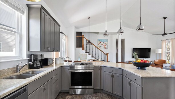 A modern kitchen with a large island, stainless steel appliances, and a view to the living area. - 7bdr w/ Private Pool, Hot Tub, Fire Pit, Walk to Beach Tidal Wave by Avantstay (Destin)