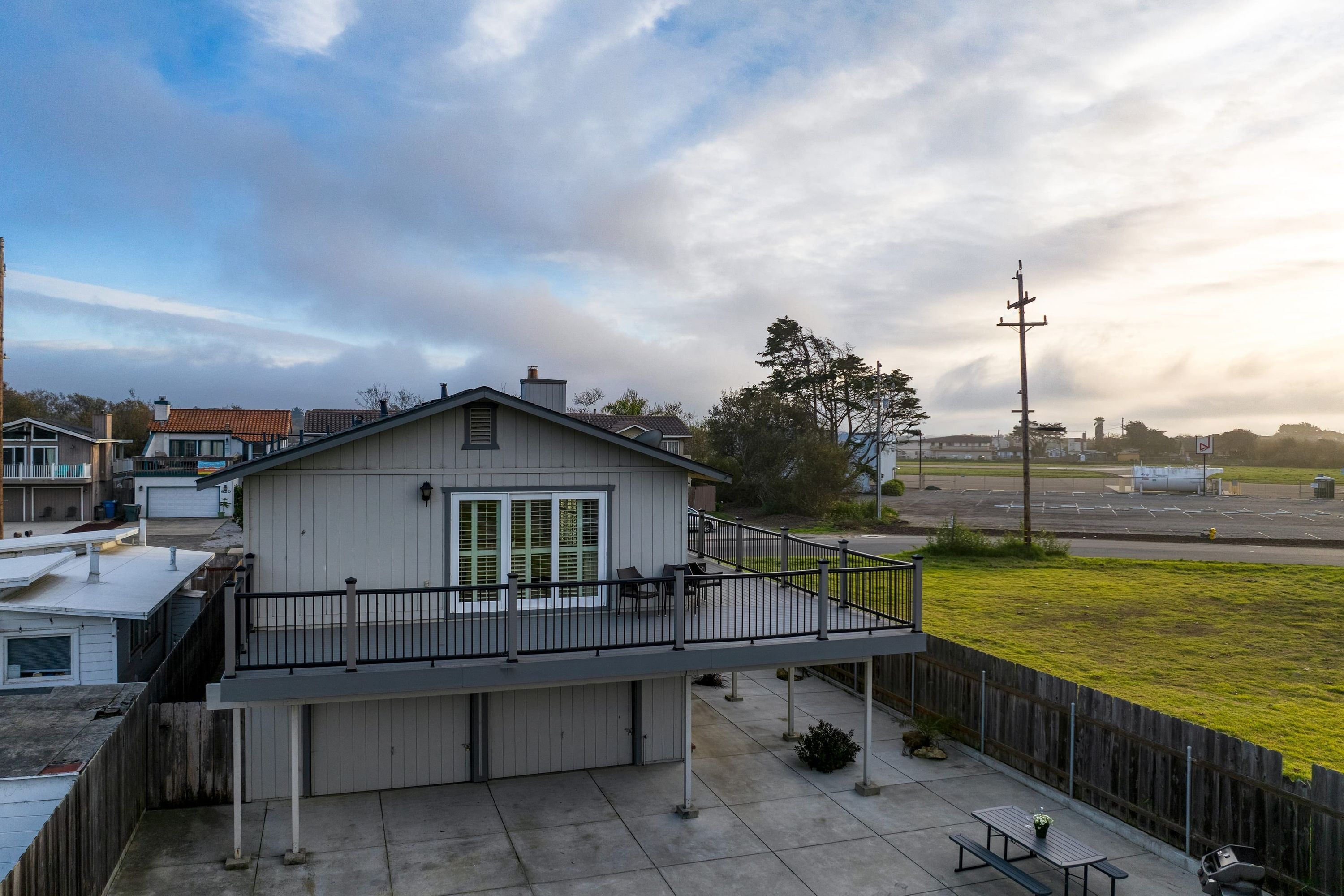 A two-story building with a balcony, a covered patio, and a view of a parking lot.