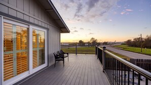 A balcony with a view of the sunset, a railing, and two chairs. - Mendel Manor by Avantstay Walk to Beach Large Deck Patio (Oceano)