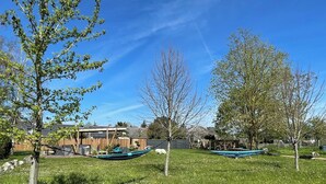 Une cour arrière verdoyante avec une terrasse en bois, un bateau et un petit abri de jardin.
