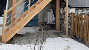 Un escalier en bois mène à une mezzanine dotée d’un mur en pierre et d’un toit en métal.