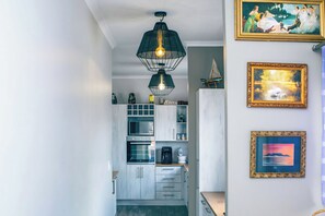 A modern kitchen with built-in appliances, a hanging pendant light, and artwork on the walls.