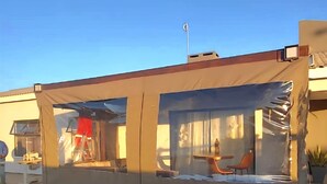 A covered outdoor seating area with a table and chairs, a flag on a pole, and a building in the background. - Spacious 3BR Family Haven in Walvis Bay – 30 Min to Swakopmund! Self-Catering (Walvis  Bay)