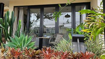 Área de pátio com diversas plantas, uma mesa e cadeiras.