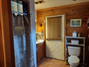 Een badkamer met een houten deur, een wastafel, een toilet en een plank met een mandje.