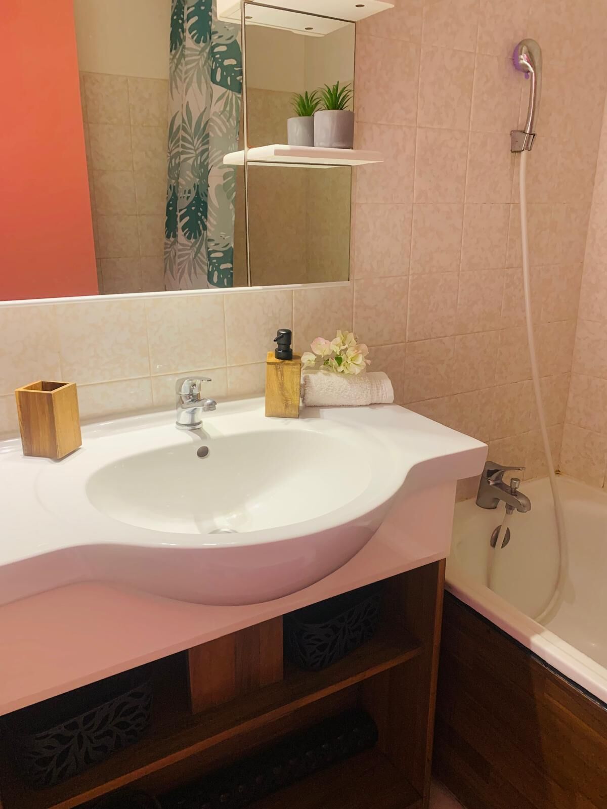 A bathroom with a white sink, a mirror, a shower, and a towel rack.