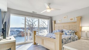 Une chambre avec une grande fenêtre, un lit, un bureau et une chaise.