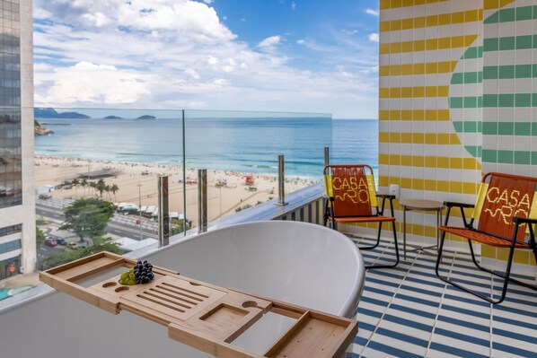 Un balcón con vista a la playa, una bañera y dos sillas con un letrero que dice 'CASA'.