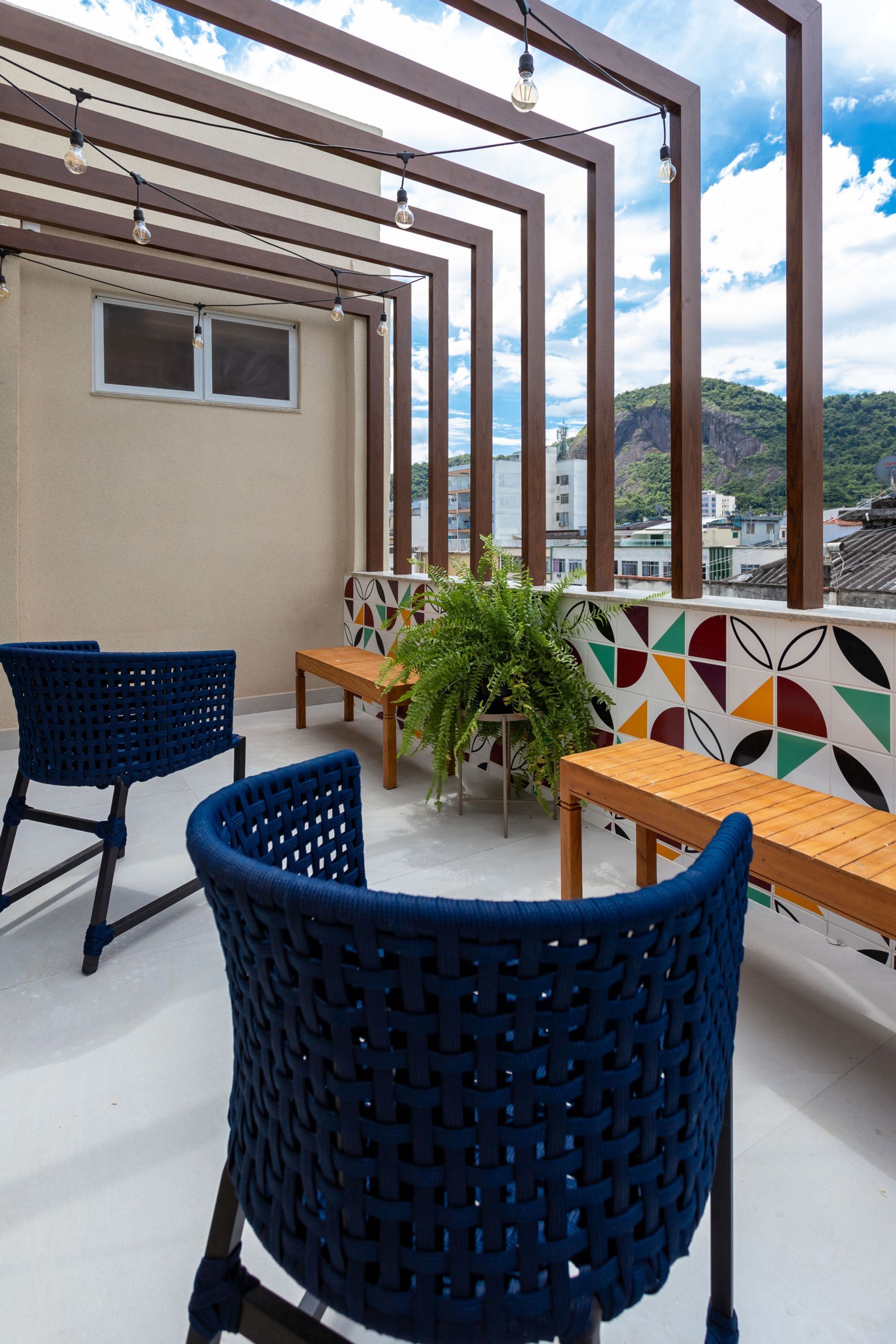 A balcony with wicker chairs, a wooden table, and a potted plant.