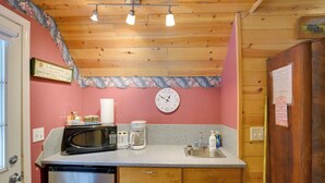 A compact kitchen with wooden cabinets, a stainless steel dishwasher, a microwave, a coffee maker, and a sink. - Walk to Trails & Butte Creek: Cozy Retreat w/ Deck (Butte Meadows)