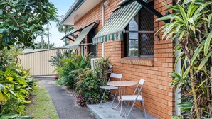 A brick house with a small patio, a table, and chairs.