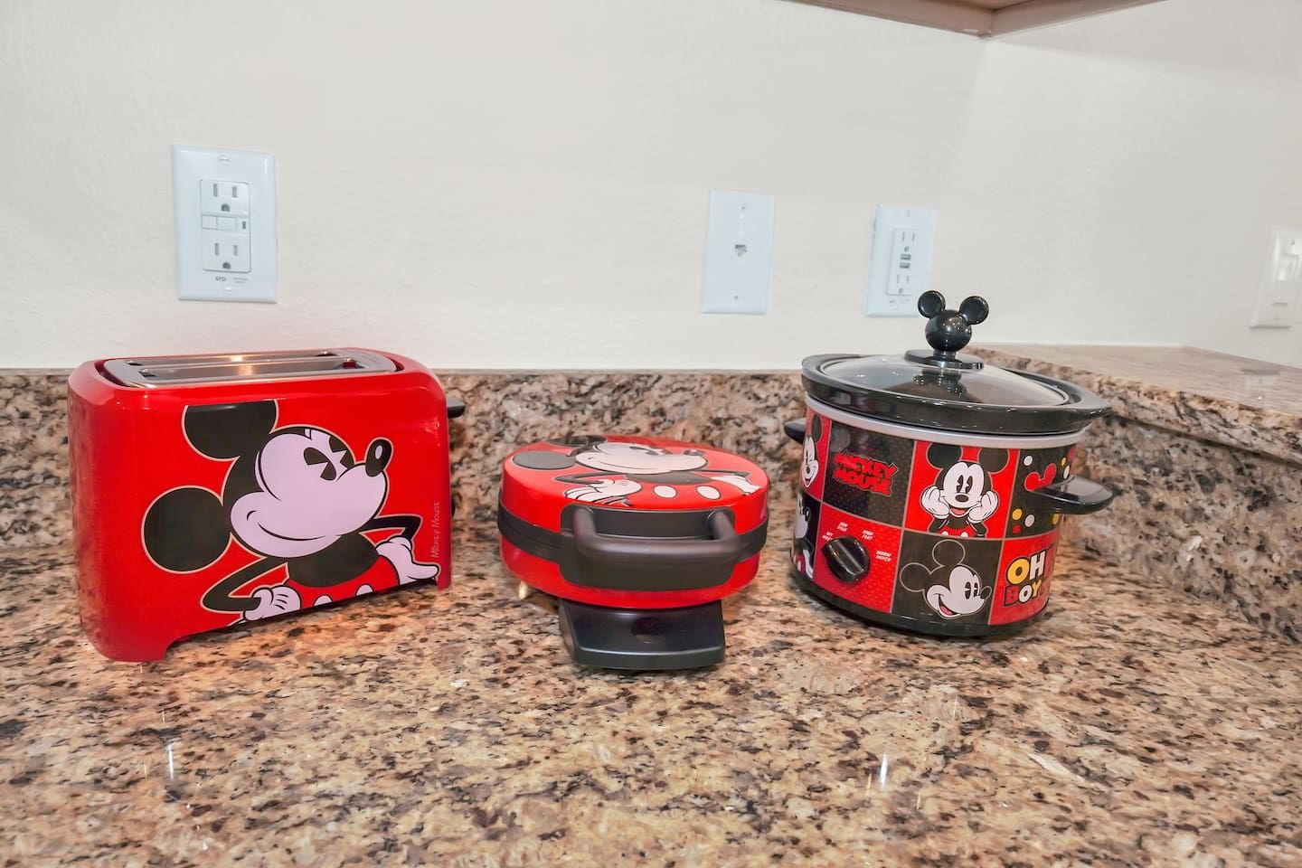 Three kitchen appliances with Mickey Mouse designs on a granite countertop.