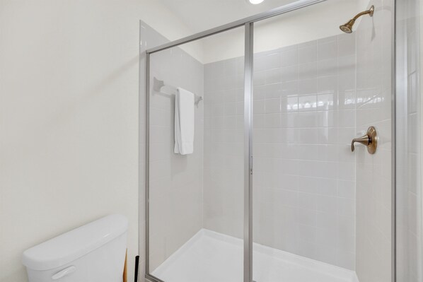 Une salle de bain moderne avec une douche à parois de verre, des carreaux blancs et des toilettes.