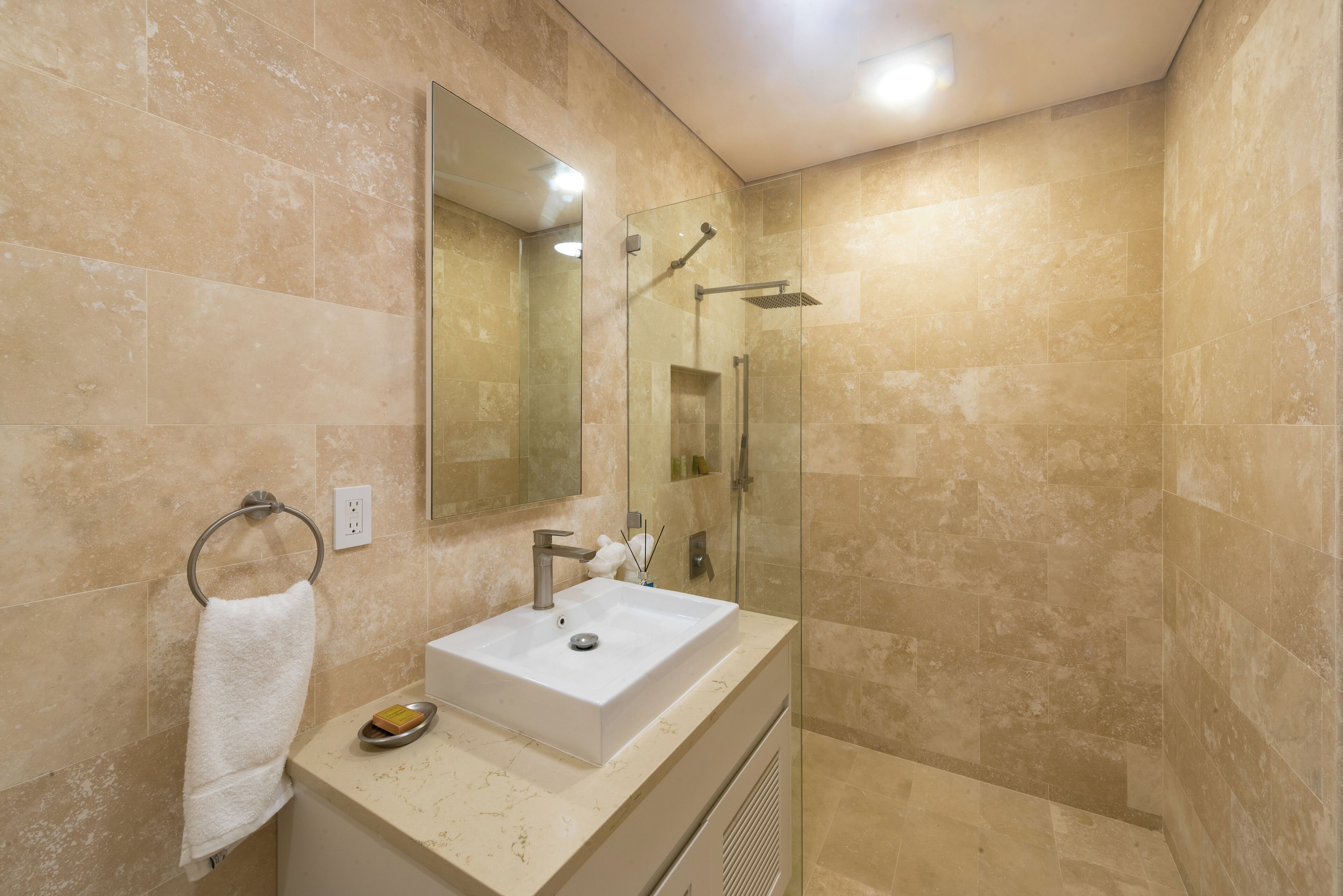 A modern bathroom with a large mirror, a sink, and a glass-enclosed shower.