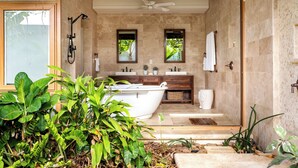 A modern bathroom with a freestanding bathtub, a ceiling fan, and a large window.
