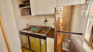 A compact kitchen with a stainless steel refrigerator, a dishwasher, and a sink. - Vista al Costanera (Santiago)