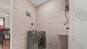 A compact laundry room with a front-loading washing machine, a marble sink, and a wooden-tiled wall. - Spacious Flat with 2 Bedrooms in CDMX (Mexico City)